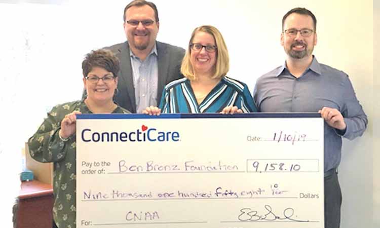 Group of people holding oversized donation check.