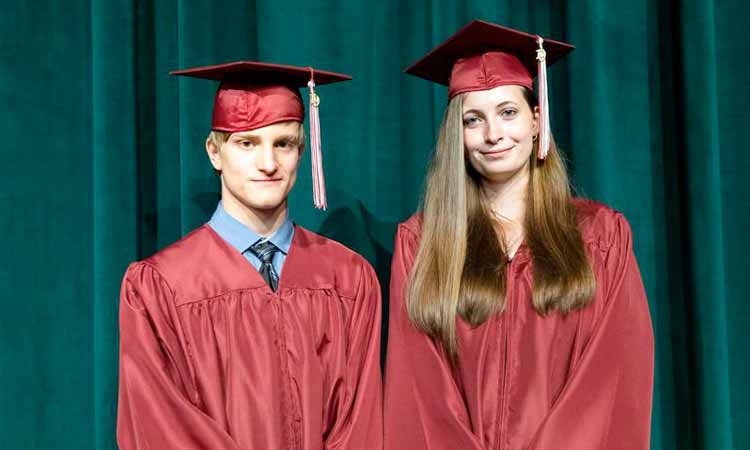 Smiling male and female Ben Bronz Academy graduates wearing cap and gown.