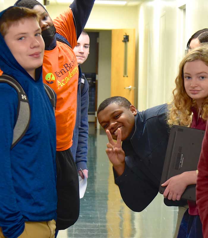 kids in hall Dyslexia & ADHD, Day School for grades 2–12. Group of students in hall, one boy making the victory symbol with his left hand.