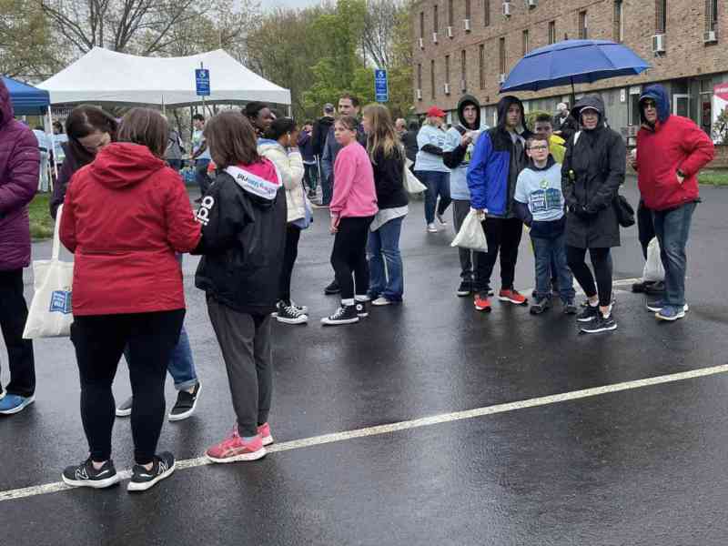 library walk - Ben Bronz Academy Group of people waiting in the rain, some with umbrellas.