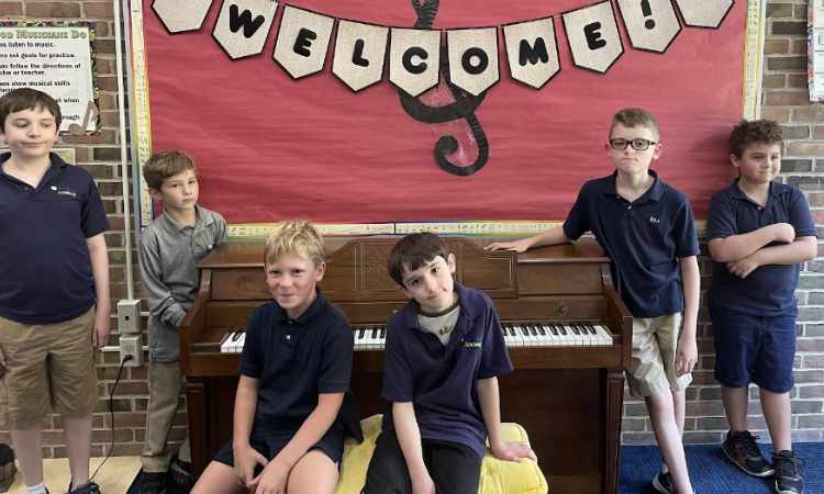 Group of male students around a piano that was donated to the school.