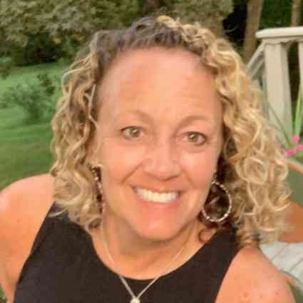 Smiling woman with wavy medium length blond hair.