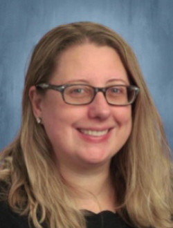 Smiling woman with glasses and long blond hair.