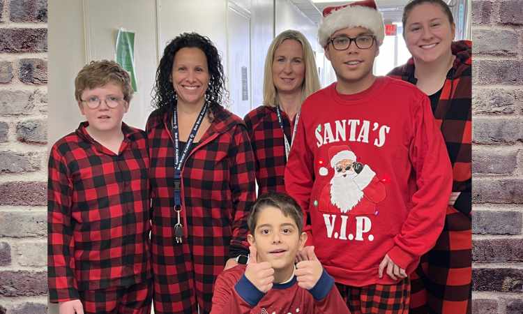 Group of adults and children dressed in black and red checker pattern holiday pajamas.