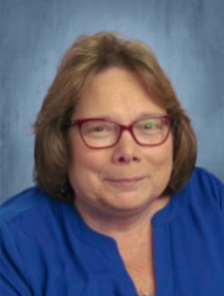 Smiling female teacher, wearing glasses.
