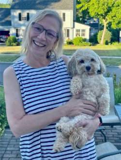 Smiling woman holding small dog in her arms.