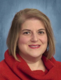 Female teacher with short dark blond hair, wearing a red sweater.