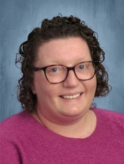 Smiling woman with curly short hair, wearing glasses.Curriculum Coordinator, Emma Lessard