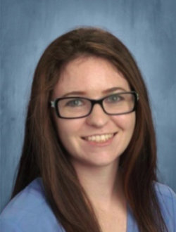 Young woman with long, dark brown hair, wearing dark rimmed glasses.