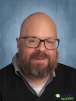 Full-bearded, smiling man with glasses.