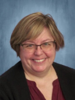 Smiling female teacher, wearing glasses.