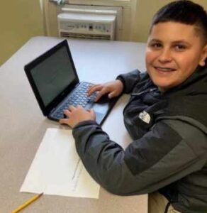 Problem-solving skills for kids. Young boy using laptop and smiling at camera.